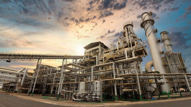 Cane sugar processing plant at sunset, with pipework, columns and gantries